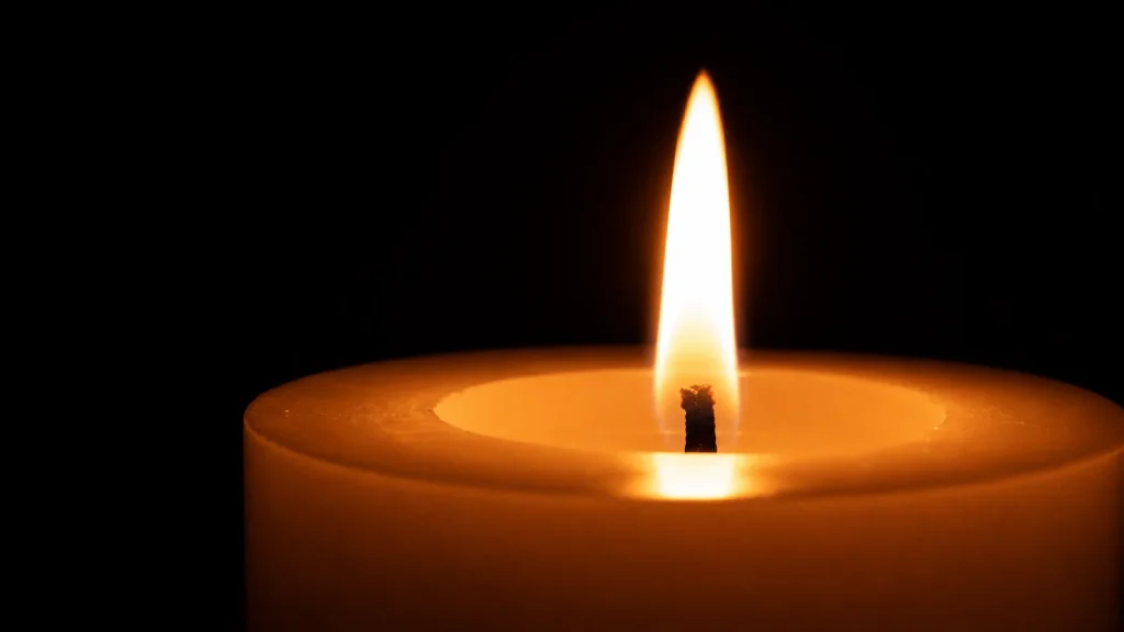 Bougie Divine allumée sur une table basse au crépuscule, dans une lumière chaude et intime